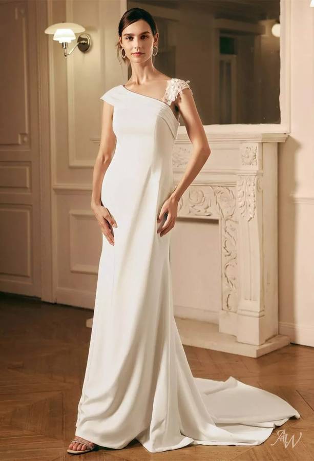 A fitted ivory crepe gown with an asymmetrical neckline and a floral appliqué strap