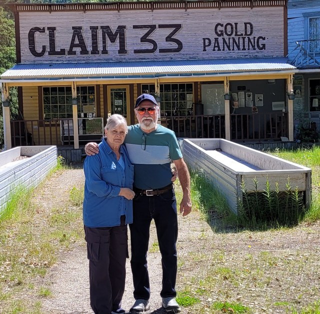 The couple arm in arm in front of the Claim 33 gold panning building