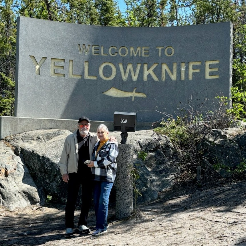 The couple standing by the Welcome to Yellowknife sign