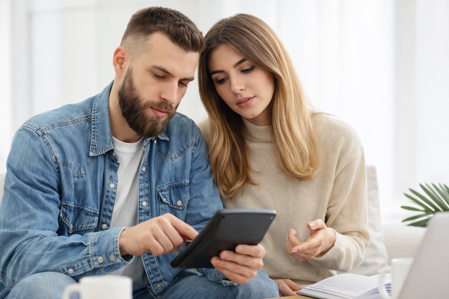 Couple reviewing their wedding guest list together on a tablet while discussing who to invite