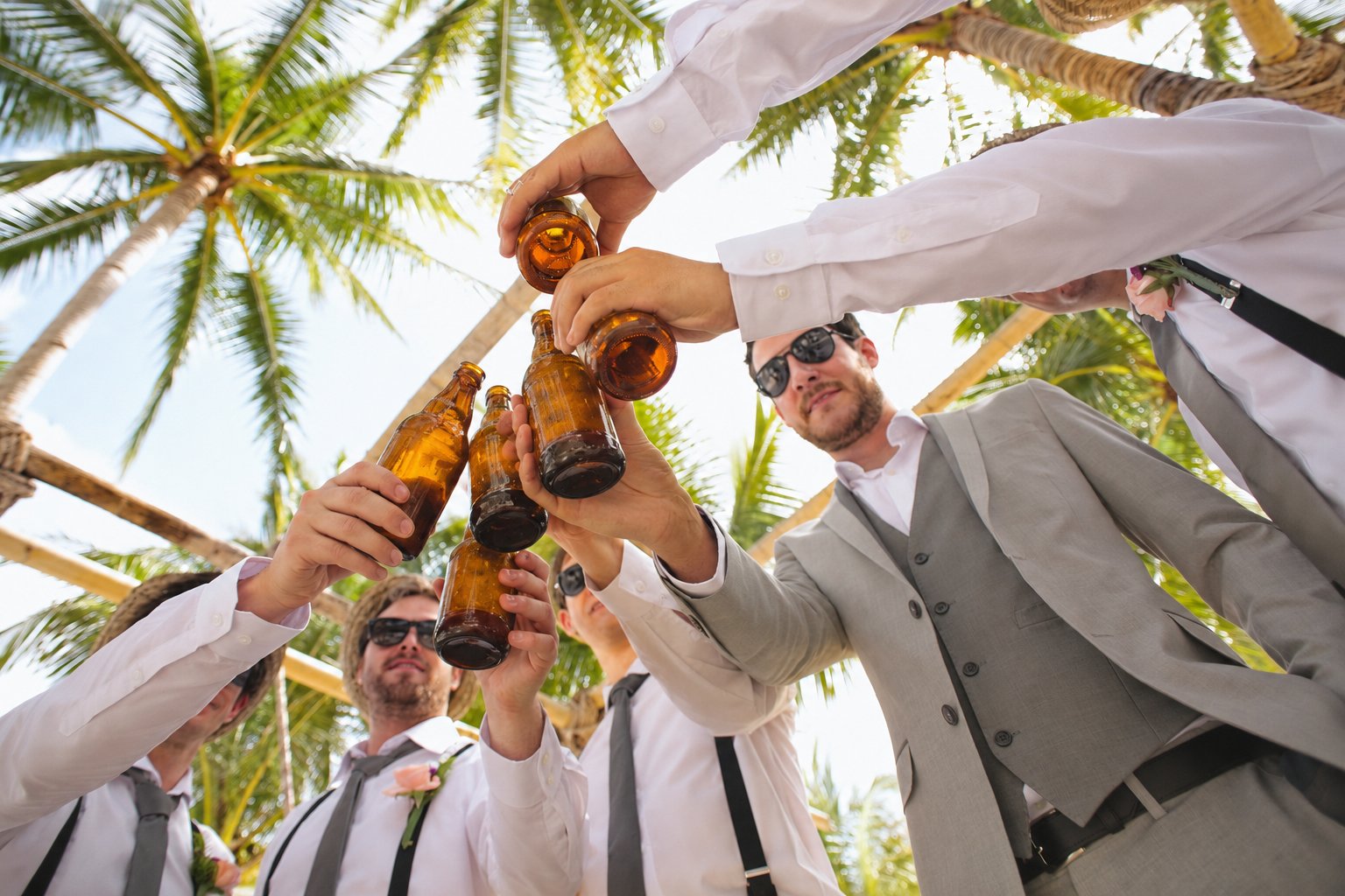 Groomsmen raising beer bottles together for a wedding toast